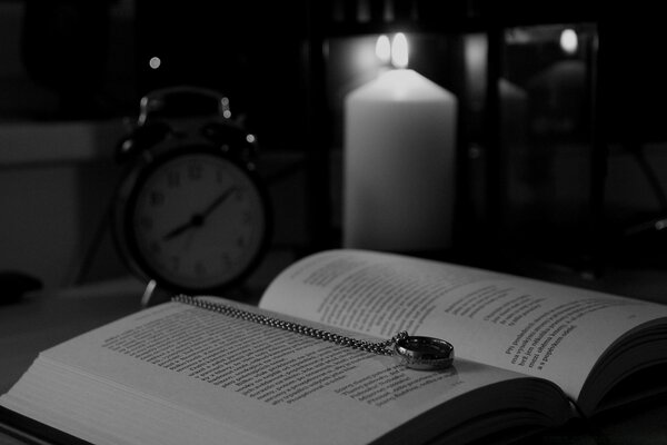 Un libro in bianco e nero si trova accanto a una candela e un orologio