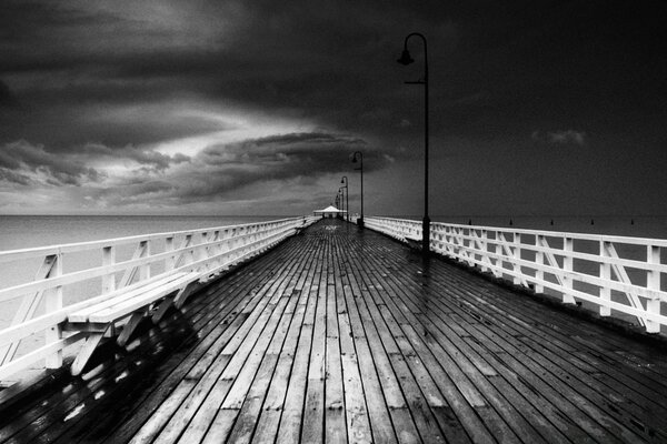 El muelle de madera se adentra en el mar en blanco y negro