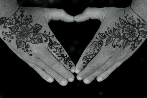 Las manos de una mujer con tatuajes rellenos simbolismo foto en blanco y negro