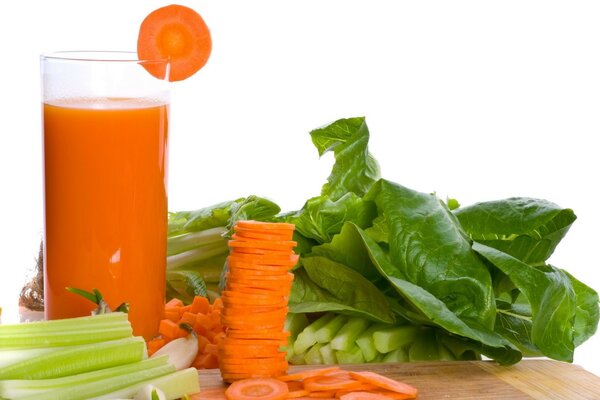 Chopped vegetables on the table and a glass of carrot juice