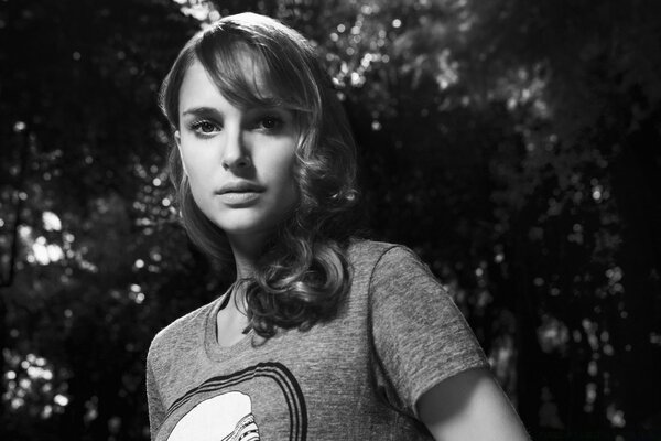 Black and white portrait of a girl against a background of trees