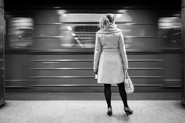 A woman stands in the subway on a black and white background