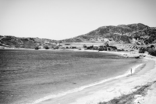 A man stands by the water in the mountains