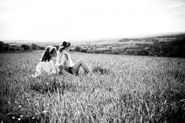 The girls are sitting in the thick grass