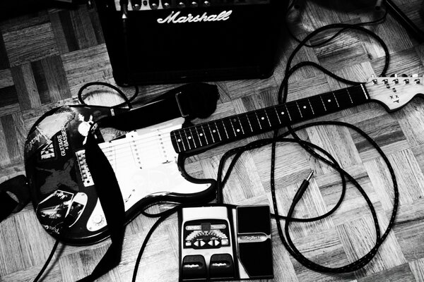 Electric guitar lying on the wooden floor next to the amplifier