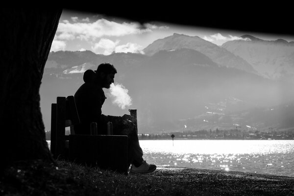 A man smokes by a pond photo