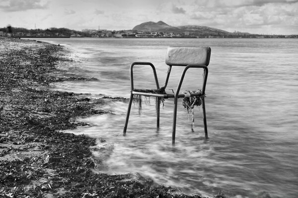 Stuhl auf dem Hintergrund des Meeres und des Strandes