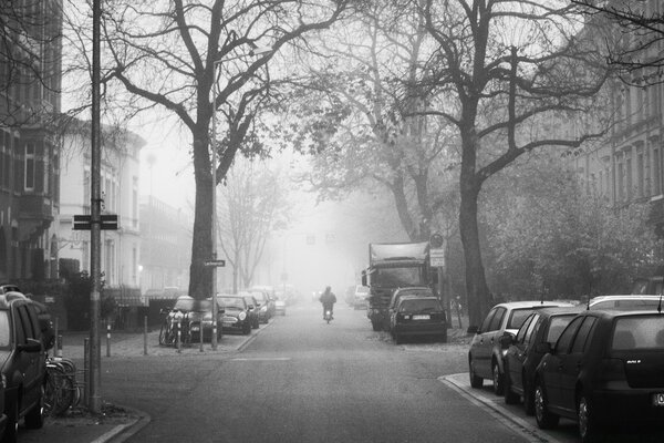 Ein Motorradfahrer fährt auf der Straße. am Straßenrand stehen Autos