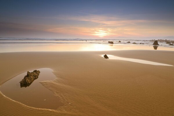 Sandy beach with rocks at sunset