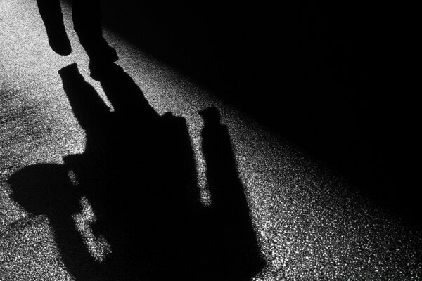 The shadow of a man on wet asphalt