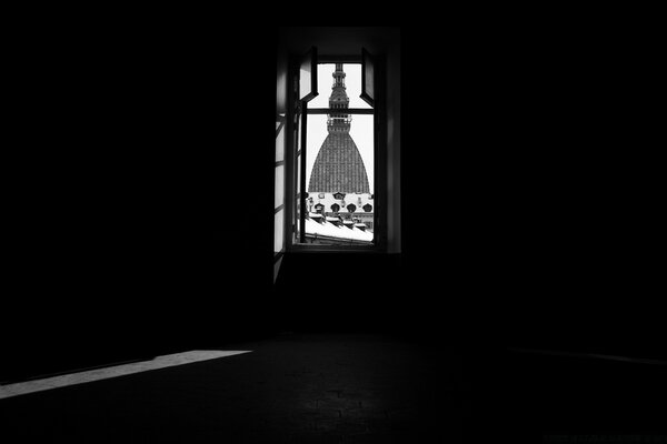 Fenêtre en noir et blanc donnant sur un bâtiment solitaire