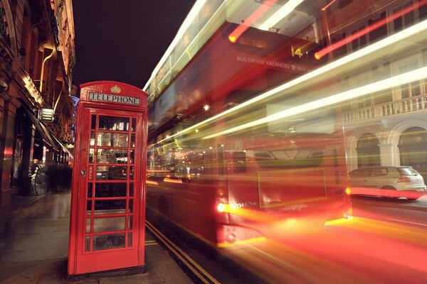 A red telephone booth and a fast moving bus