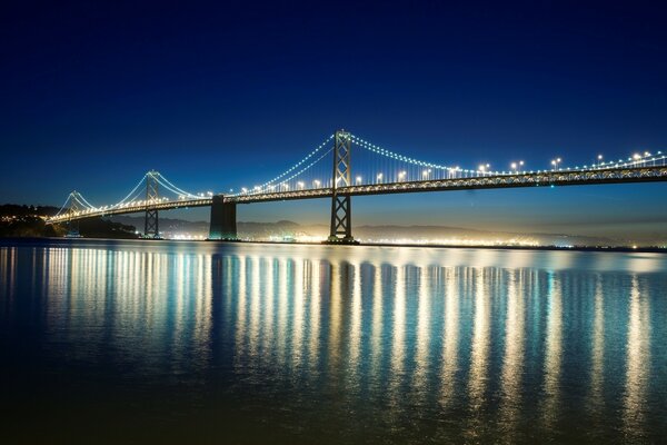 Puente nocturno iluminación reflejo en el agua