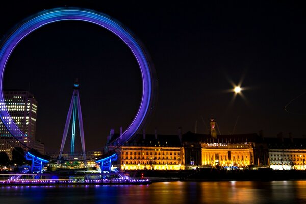 Night city in lights on the river bank