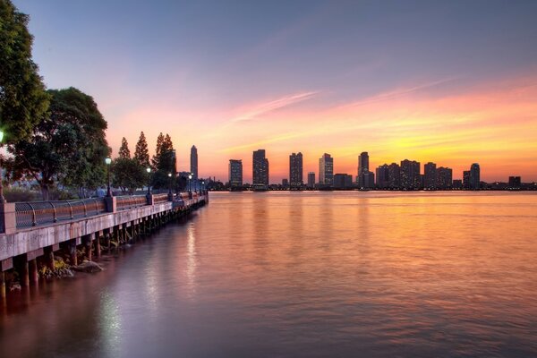 Evening in the city. The bridge goes into the distance. High-rise buildings against a bright sky