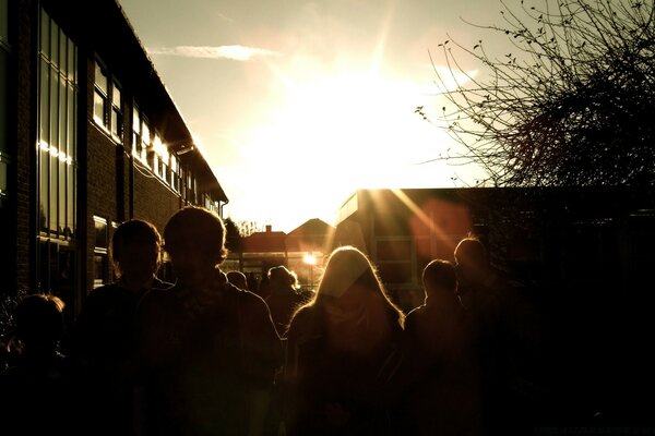 Dark silhouettes of people against the background of the sun