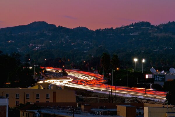 Colored road. Sunset near the mountains. Beautiful mother-of-pearl sky