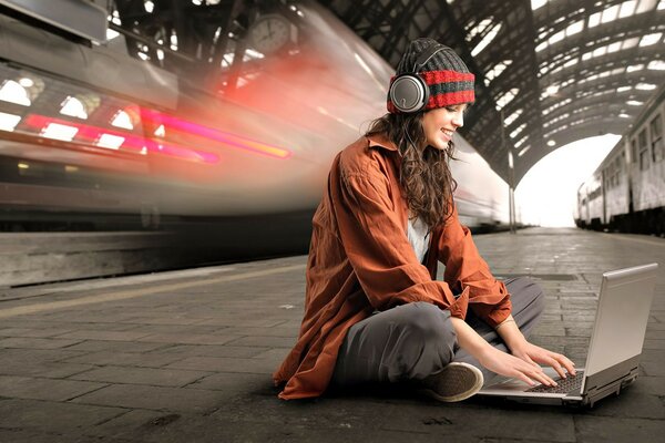 Una chica con auriculares se sienta detrás de una computadora portátil