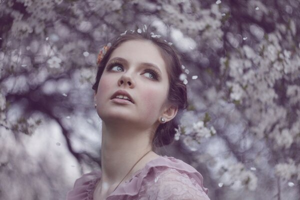 The girl looks to the side against a background of white flowers