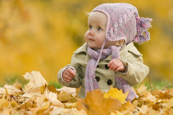 A child plays with leaves in an autumn park