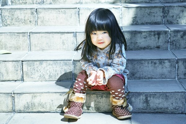 A little Japanese woman is sitting on the stairs