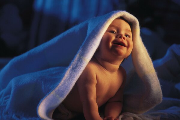 Retrato de un niño feliz bajo las mantas