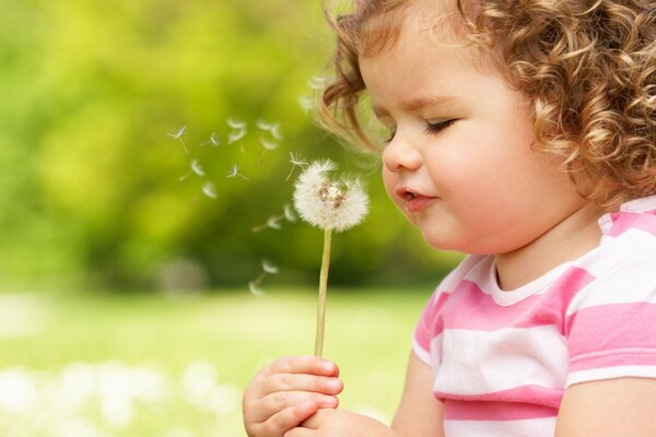 Niña soplando en dientes de León