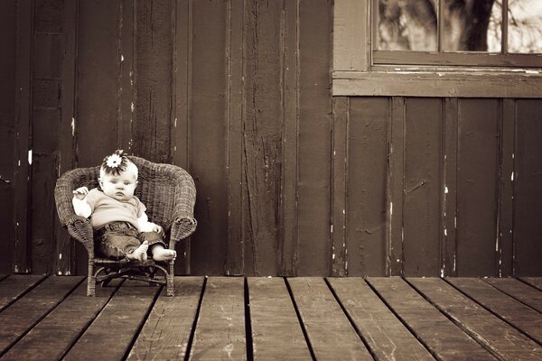 The child is resting on a wicker chair