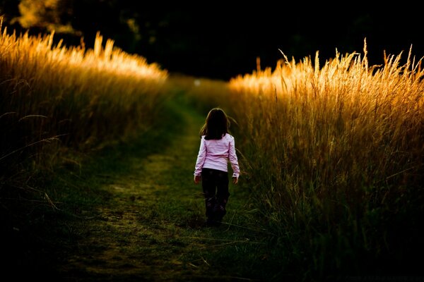 A girl on the background of the sunset goes into the distance