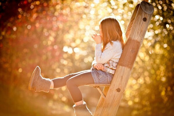 A girl is sitting on the stairs on a sunny day