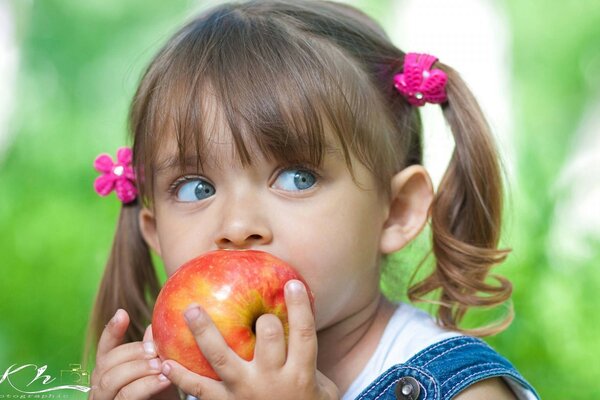 Menina comendo uma maçã madura