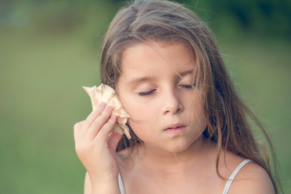 La ragazza ascolta la conchiglia