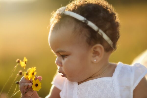 A little girl sniffs a flower