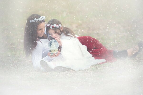 Mamma e figlia guardano il globo di neve