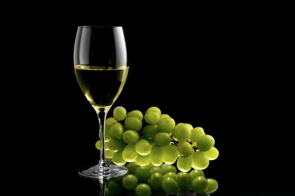 White wine in a glass near white grapes