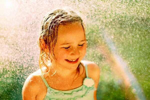 A girl in the rain rejoices in a rainbow