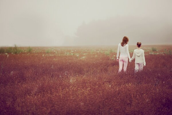 Mãe e filha caminham no campo ao pôr do sol