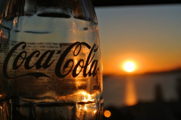 En la imagen cerveza Coca cola y puesta de sol