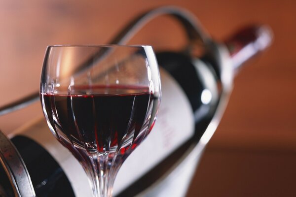 Verre de vin rouge sur fond de bouteille