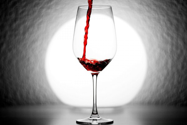 倒红葡萄酒与透明玻璃上的背景光