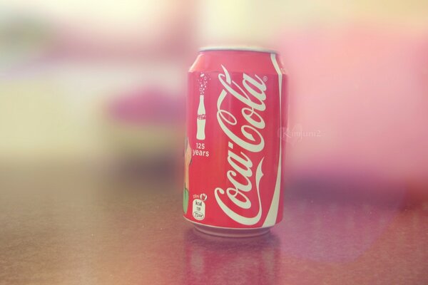 A delicious can of Coca Cola is on the table