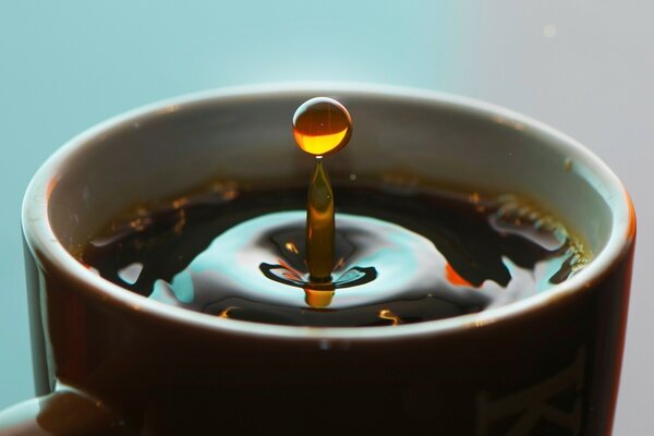 A drop of hot tea falling into a mug