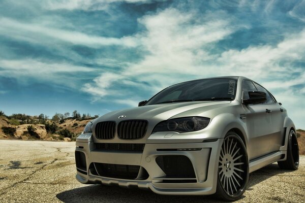 Ein graues BMW-Auto in einem bergigen Gebiet unter blauem Himmel