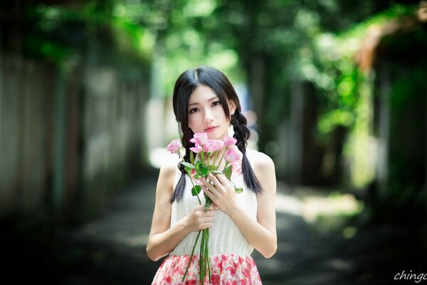 Fille asiatique avec des fleurs roses à l extérieur