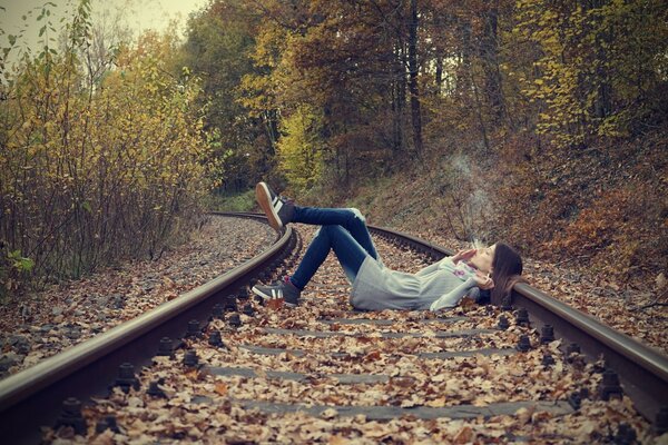 A girl smokes on the railway tracks