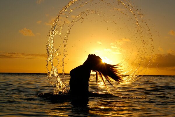 Mädchen im Meer bei Sonnenuntergang