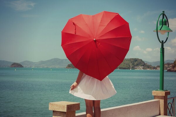 Fille avec un parapluie rouge en forme de coeur