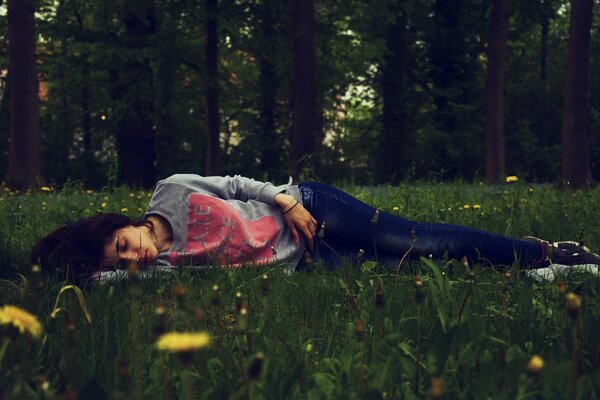 A girl sleeps in a field of dandelions