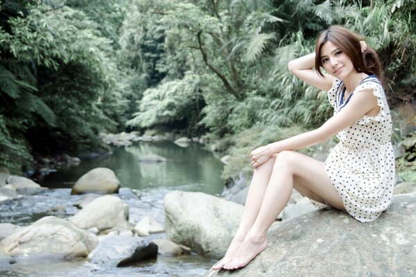 Hermosa chica en un arroyo en el bosque