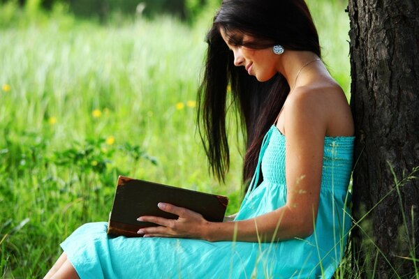 A girl with a book is sitting on a tree